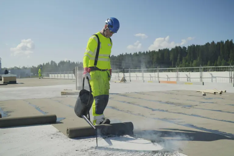 Katehuolto Oy:n asentaja tekee bitumikermikattoa liikehuoneiston katolla.