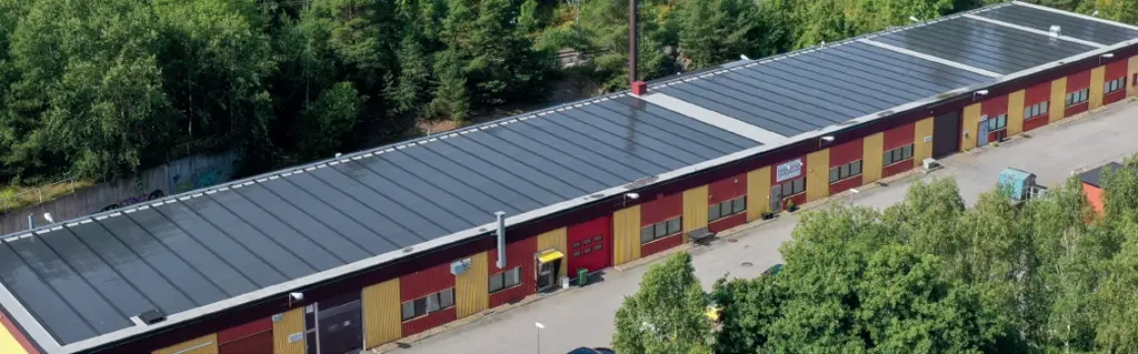 Ilmakuva suuresta varastosta, jossa on katolla ohutkalvoaurinkopaneelit.
